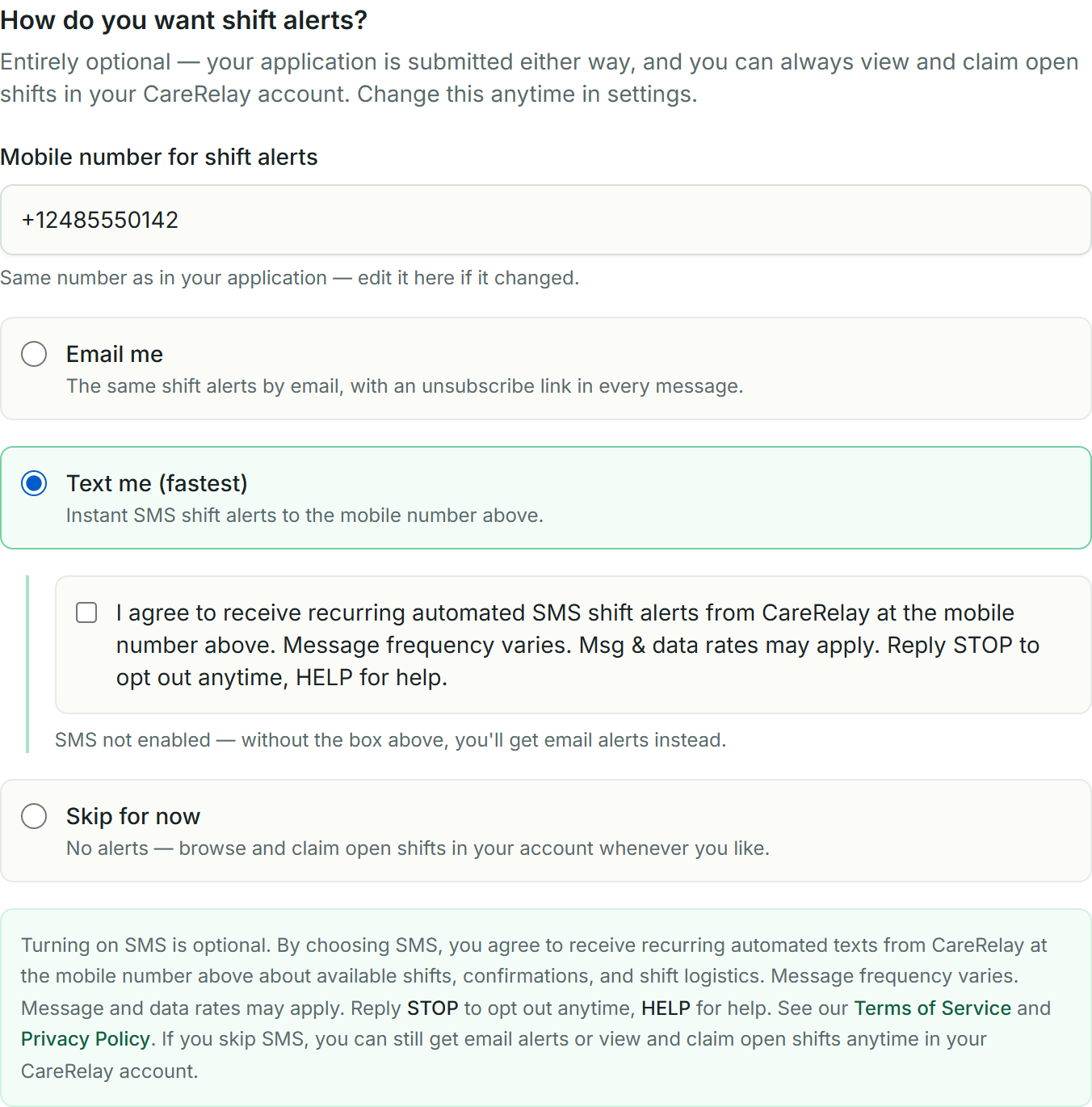 The CareRelay worker application notification step: the worker's editable mobile number, alert options with Email pre-selected by default, and — once Text me is chosen — a standalone unchecked consent checkbox above the full SMS disclosure with Terms of Service and Privacy Policy links.